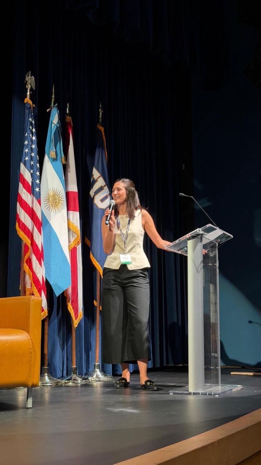 Justina Bruera hablando en un escenario junto a banderas