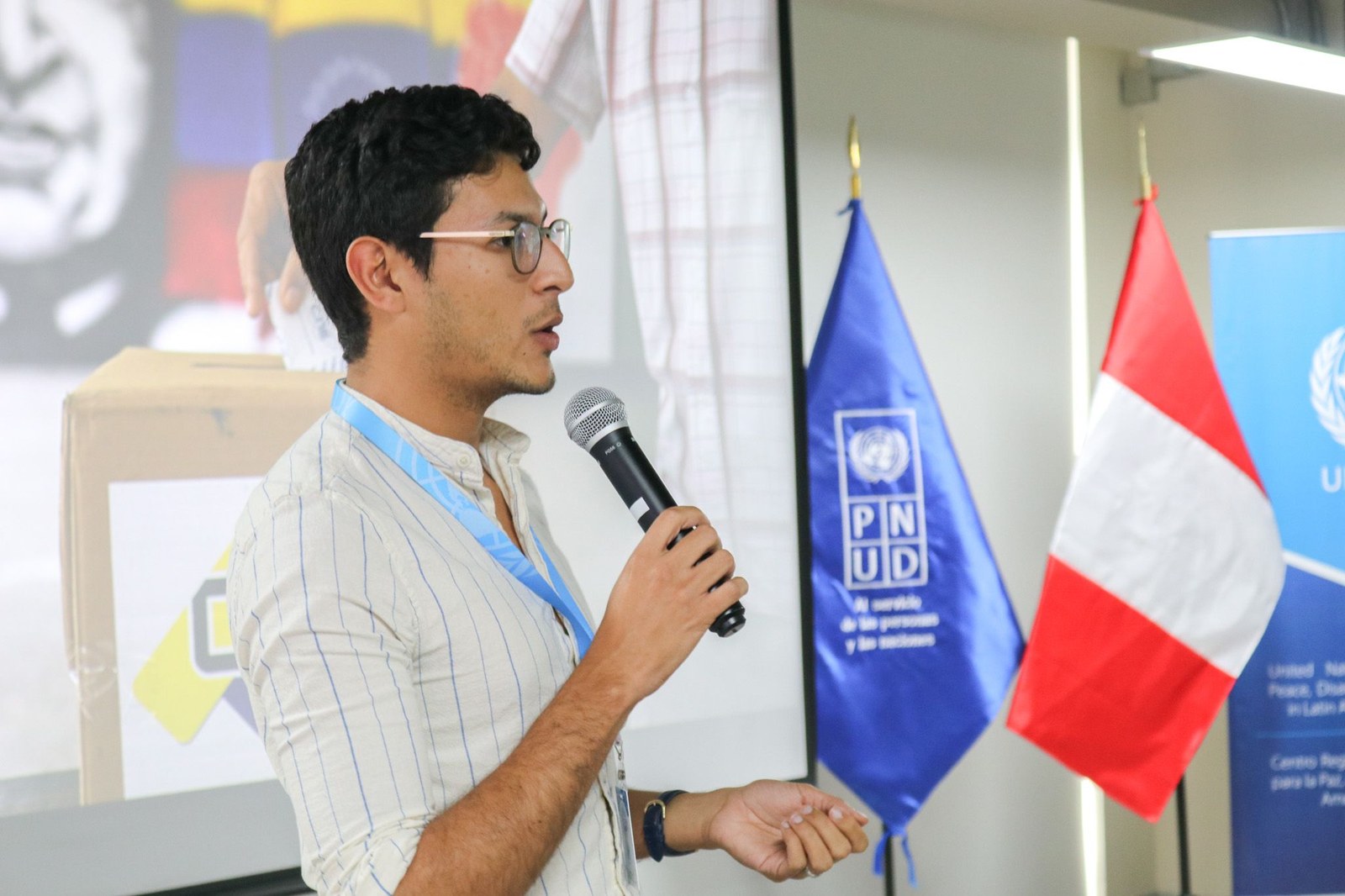 Luis Alvarado-Bruzual hablando en un evento junto a una bandera del PNUD